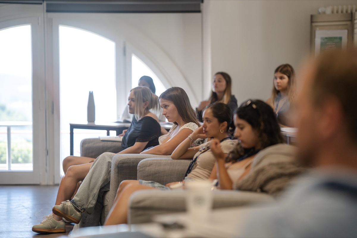Residents of UNCODED on sofas in a bright room, listening