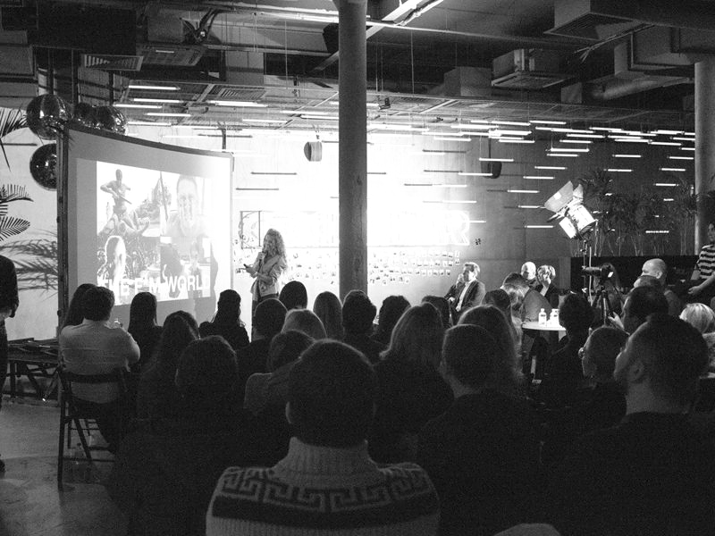 A talk in a full hall, seen from the back of the audience