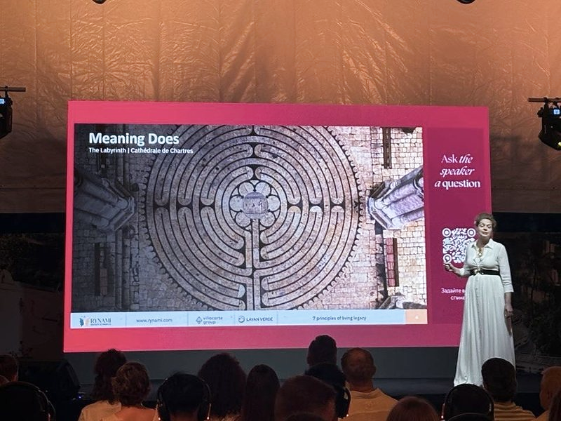 Ryna Mi on stage in front of a slide titled Meaning Does
