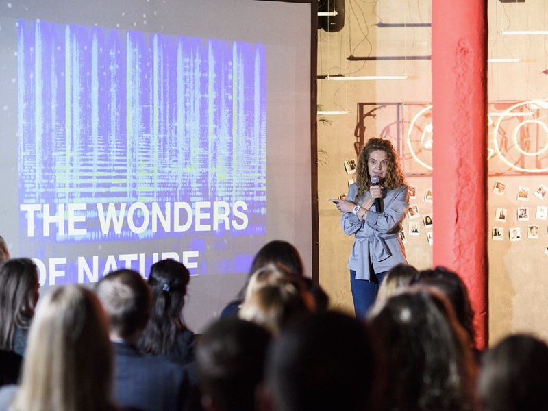 Ryna Mi speaking to a full room in front of a slide titled The Wonders of Nature